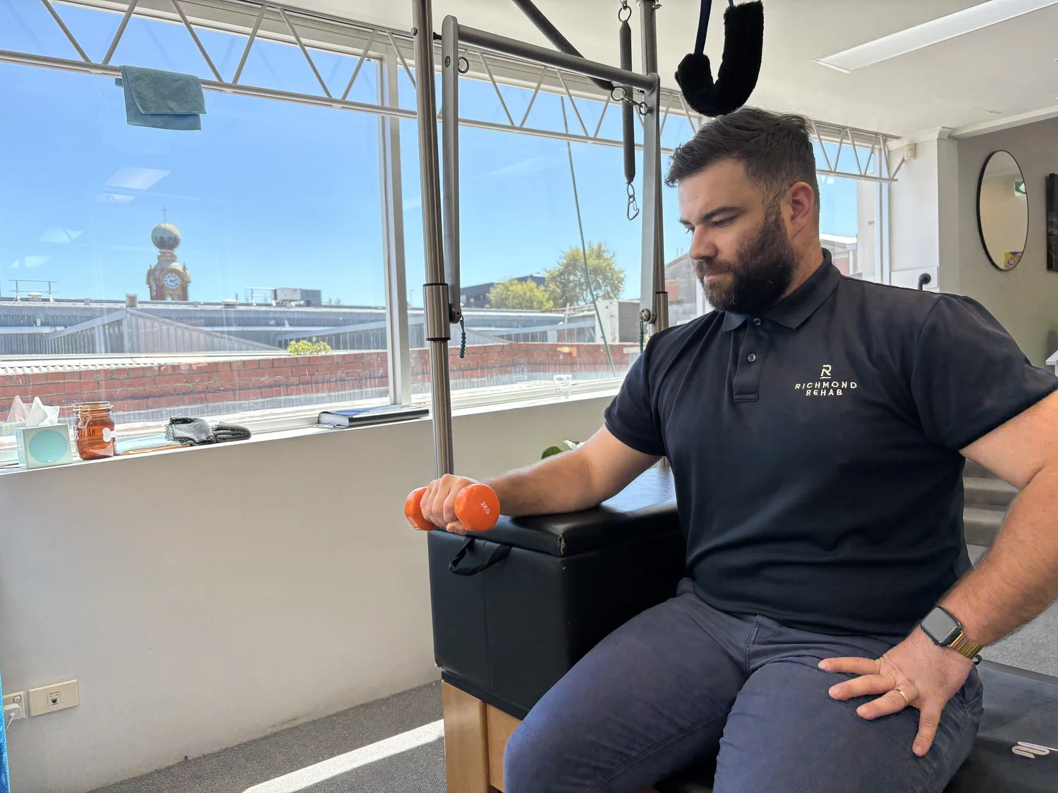 A physiotherapist demonstrating a dumbbell exercise in the Richmond Rehab Pilates studio